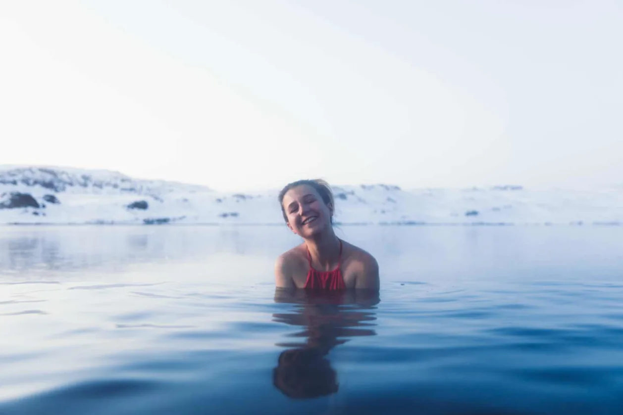 Female solo traveler in red swimsuit enjoying thermal pool in Reykjavik